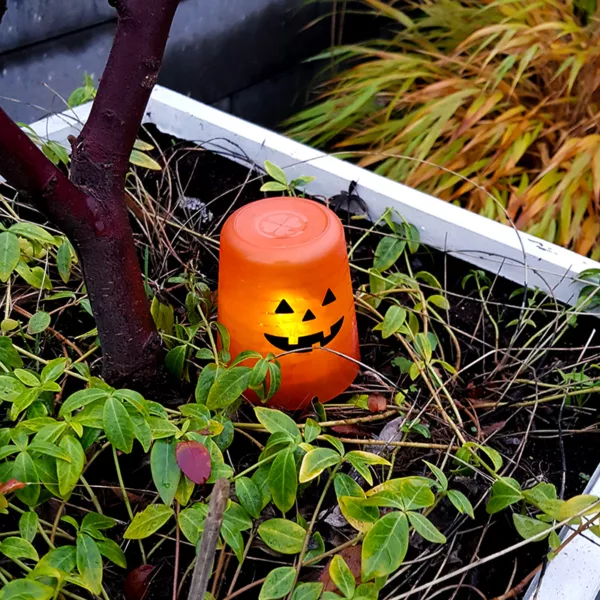En orange plastmugg har blivit Halloween-lykta med hjälp av ett litet pumpa-ansikte och ett led-ljus.