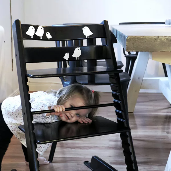 White birds on a black Tripp Trapp highchair.